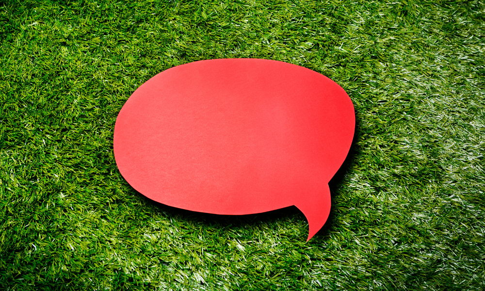 Image shows a light red speech bubble on top of some grass
